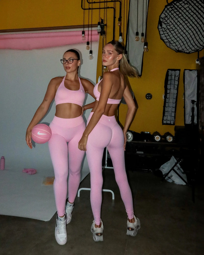 שתי דוגמניות לובשות טייץ ורוד מחטב מסדרת AURA של Inner Dragon. גזרת V וכיווץ נסתר מדגישים את הקימורים בגב.