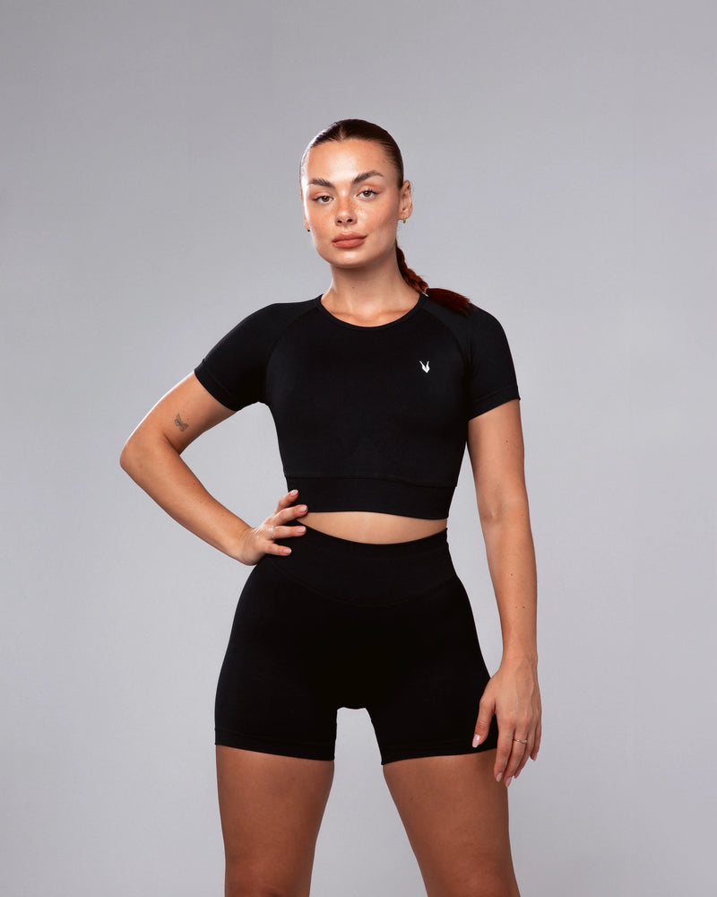 דוגמנית לובשת טופ קצר ושורט ספורט מחטב שחור HERA BLACK של אינר דרגון – טייץ מחטב לאימונים, גזרה גבוהה, בגדי ספורט לנשים, אופנת כושר חדשנית