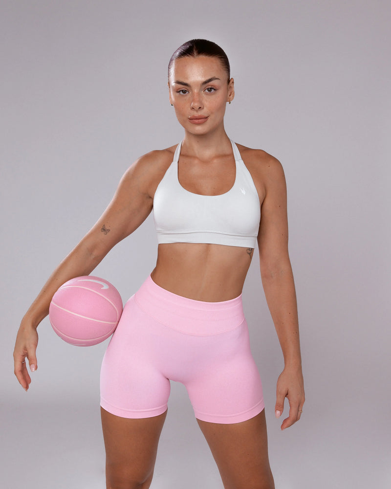 דוגמנית עם שורט ספורט ורוד מחטב של Inner Dragon, טופ לבן וכדור כדורסל, לוק אופנתי ומחטב לאימוני כושר לנשים. מבית אינר דרגון.