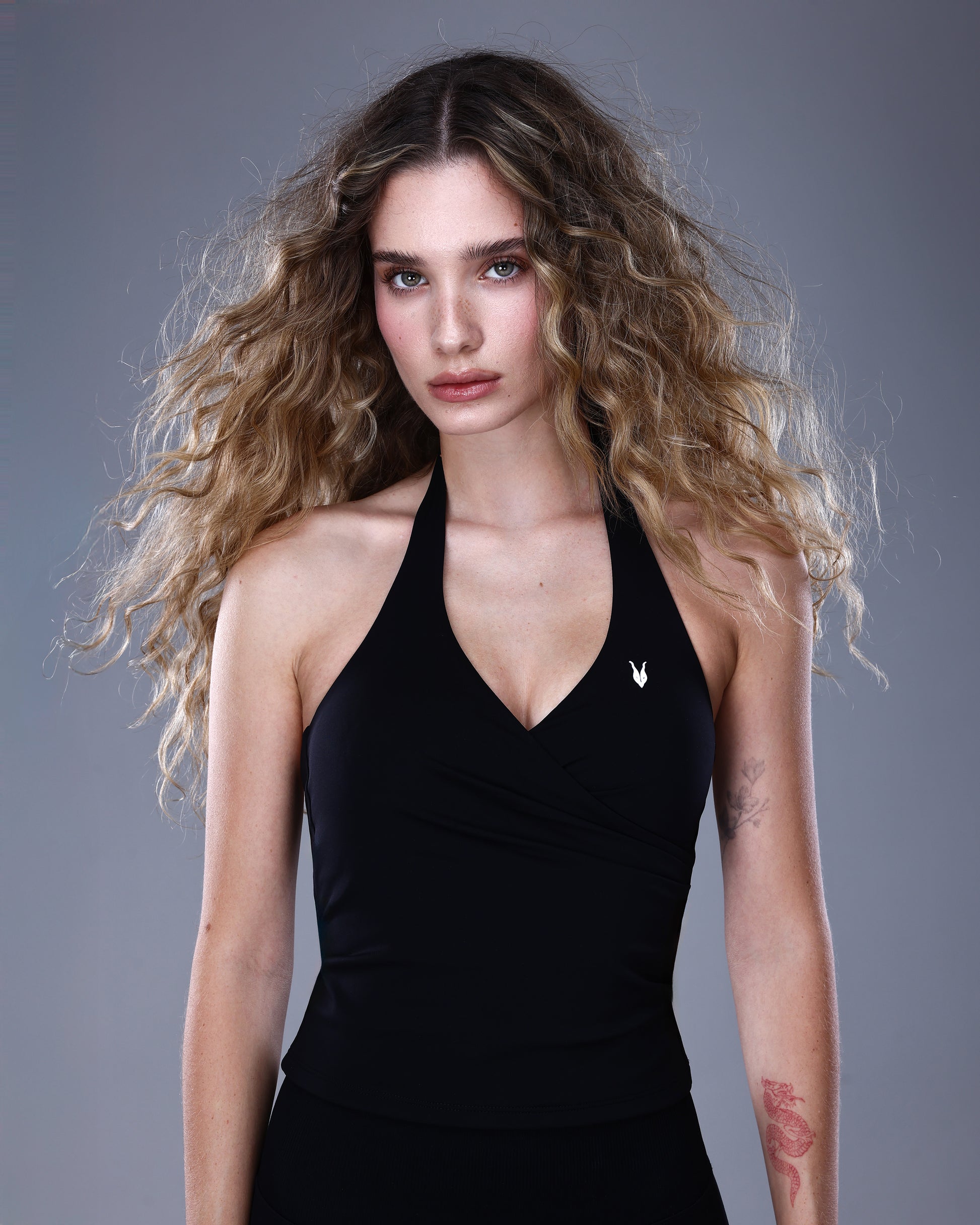 תקריב על גופיית NAIA BLACK מבית Inner Dragon – גופיית ספורט שחורה בגזרת מעטפת עם מחשוף V וכתפיות צוואר, מבד אלסטי חלק. מראה אלגנטי ומחטב המשדר עוצמה ונשיות טבעית.