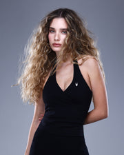 גופיית ספורט שחורה לנשים מבית Inner Dragon מדגם NAIA BLACK – גזרת מעטפת אלגנטית עם מחשוף V, קאפ נשלף ובד אלסטי רך. מושלם לאימוני יוגה, פילאטיס וסטייל יומיומי.