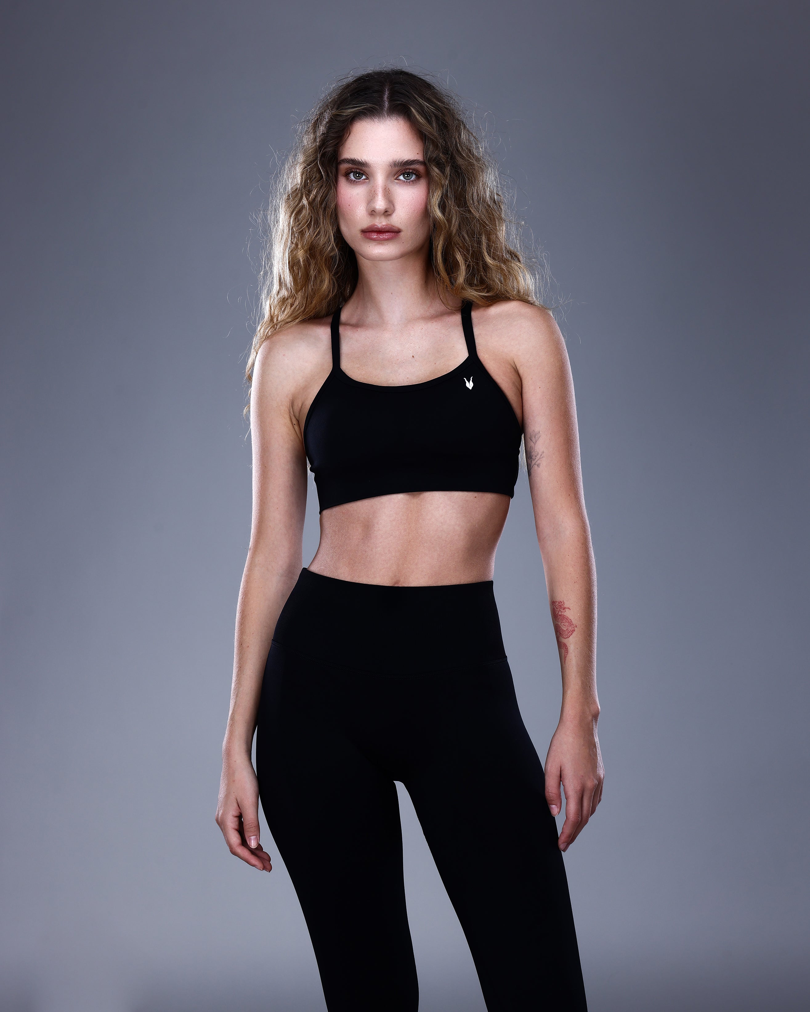 טופ ספורט NOVA BLACK של Inner Dragon – תצוגת קדמית של טופ שחור בגזרת קרוס בגב, עשוי בד אלסטי ומחטב בטכנולוגיית seamless. מראה אלגנטי ונקי המשלב בין תמיכה לנוחות באימוני כושר וסטייל יומיומי.