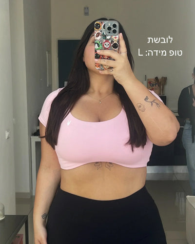 טופ ספורט ורוד לנשים במידה גדולה (L) – הדגמה על גוף אמיתי, טופ בגזרת VENUS של אינר דרגון, מתאים לפלוס סייז, תמונת ניסיון למדידת התאמה ומראה מחמיא  לנשים במידות גדולות.
